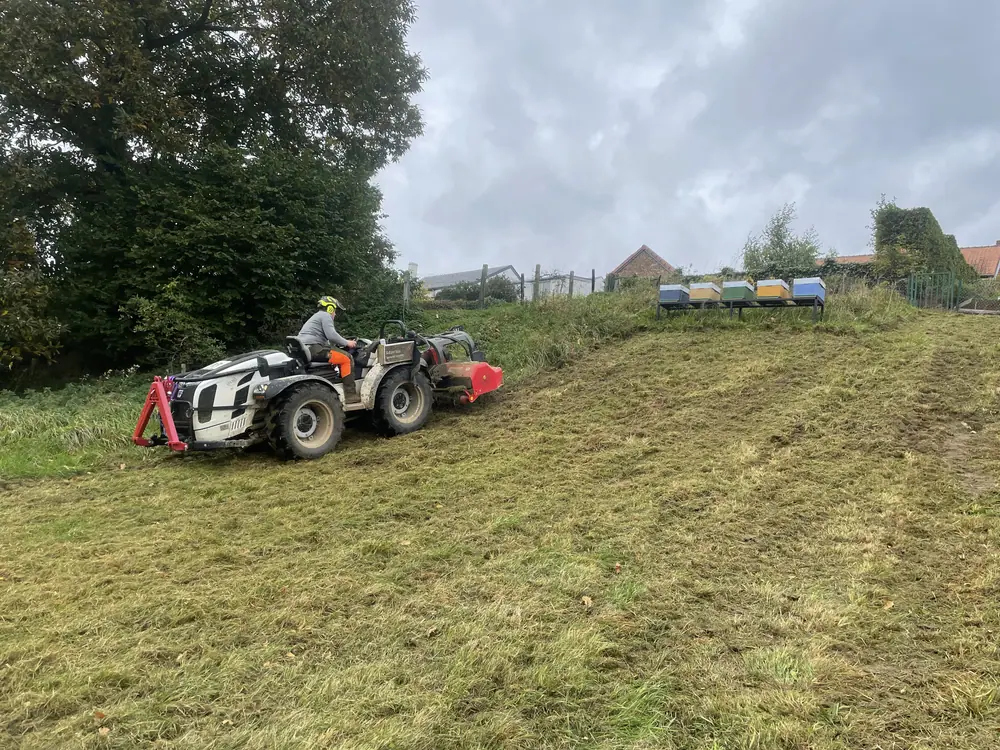 Gyrobroyage d’un talus au tracteur, avec des ruches en arrière-plan
